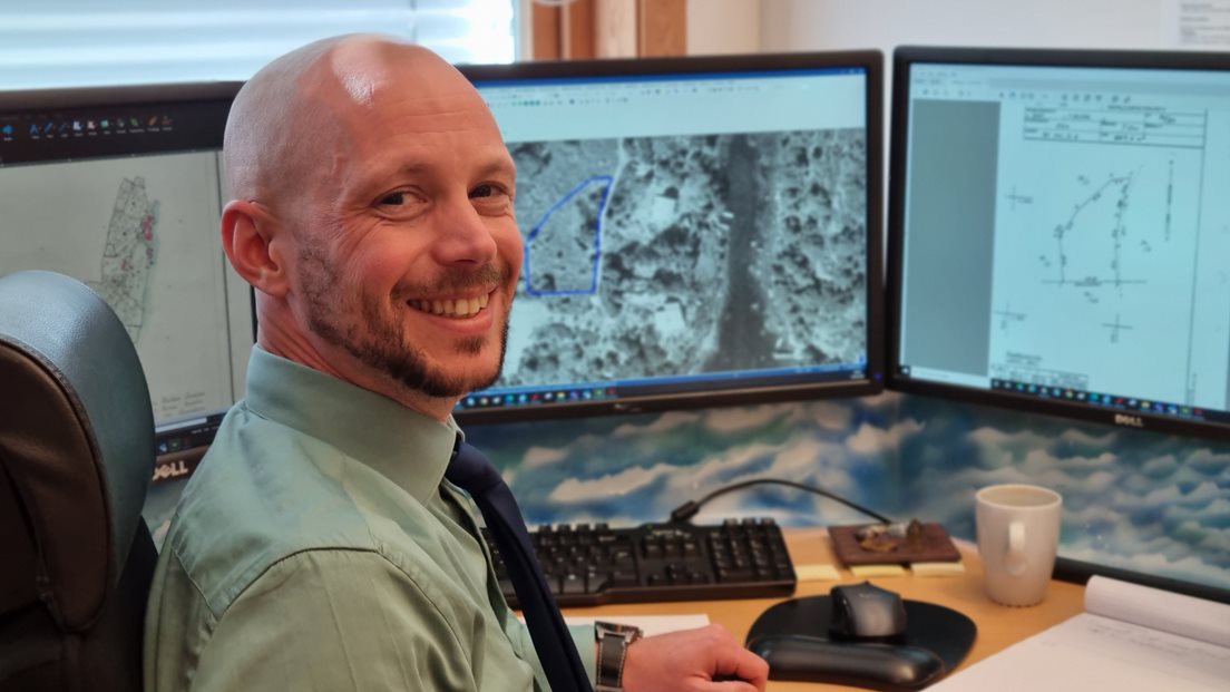 Petter Fidje foran pc med historiske ortofoto på skjermen foran seg