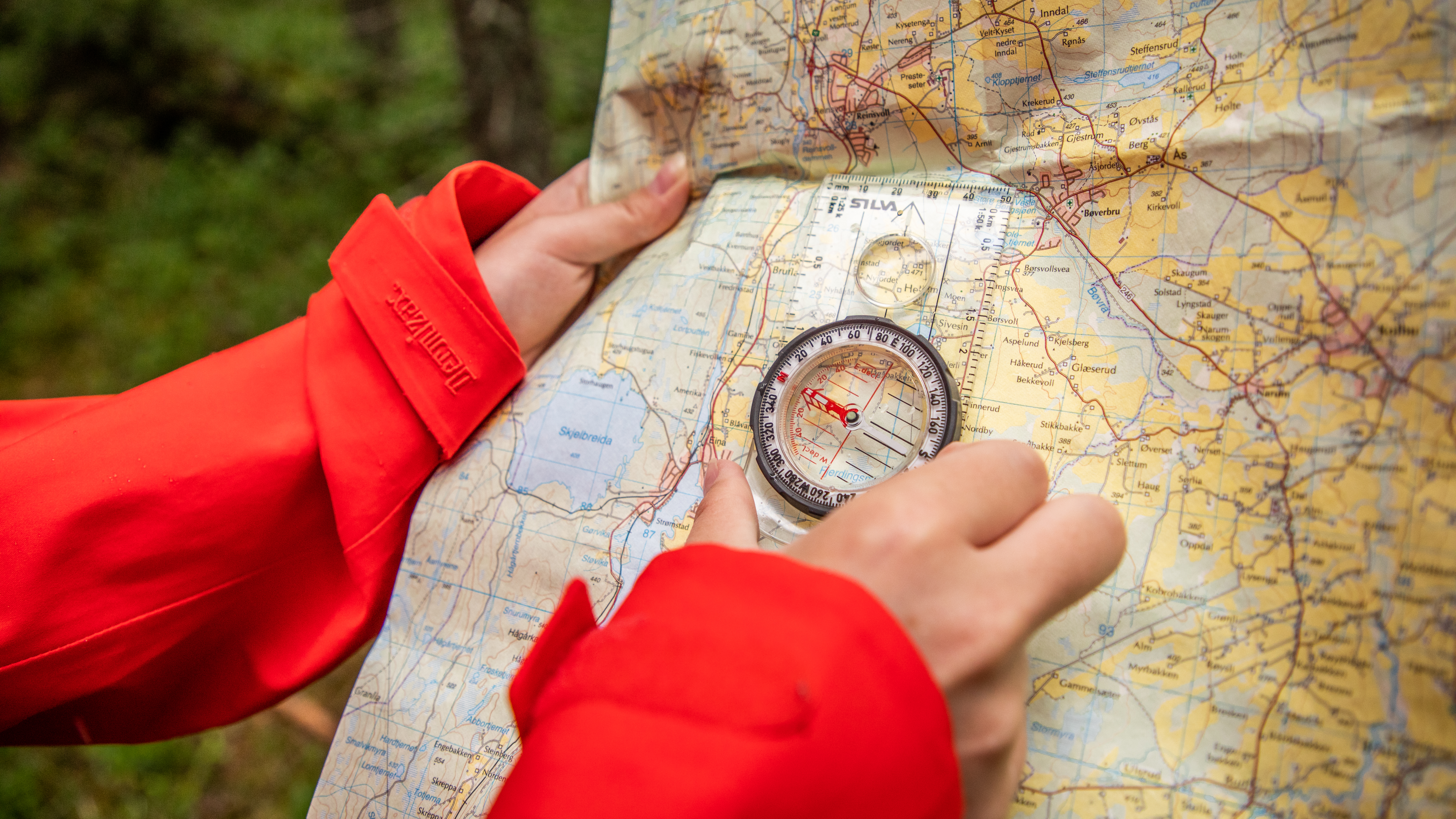 Kvinne bruker kompass og kart for å ta ut kursen