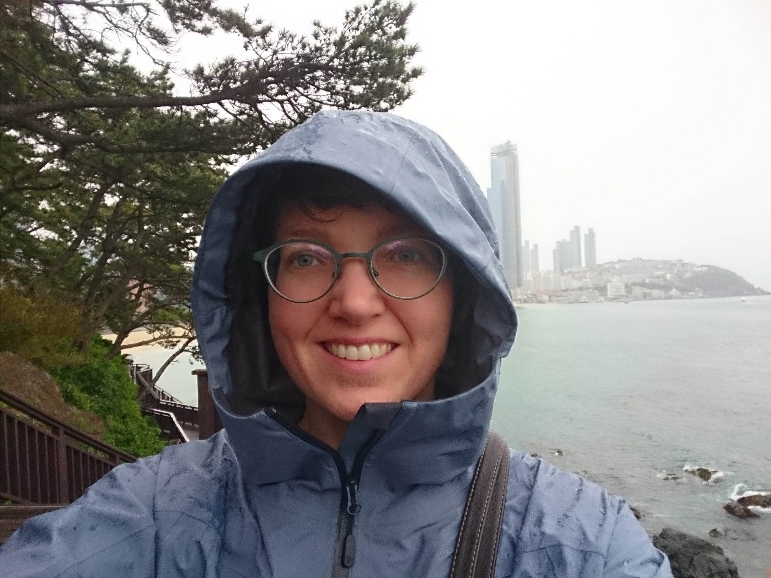 Selvportrett av Oda Roaldsdotter Ravndal. Byen Busan i Sør-Korea skimtes i bakgrunnen. Foto.